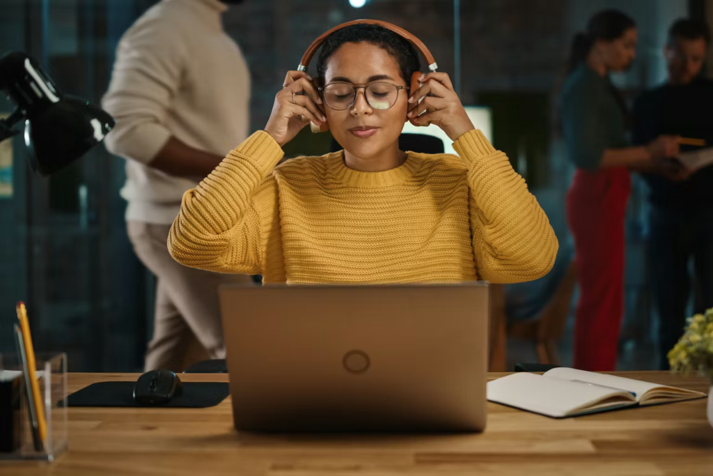 Woman putting headphones on to start listening to music while working.