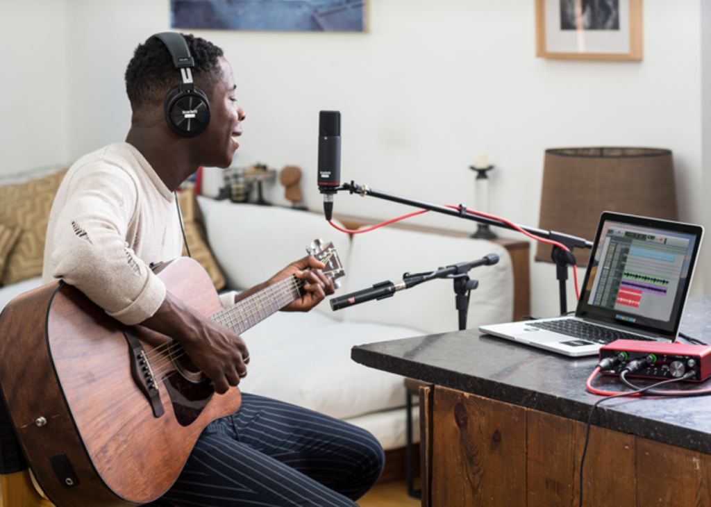 Independent musician recording music in a home studio setup