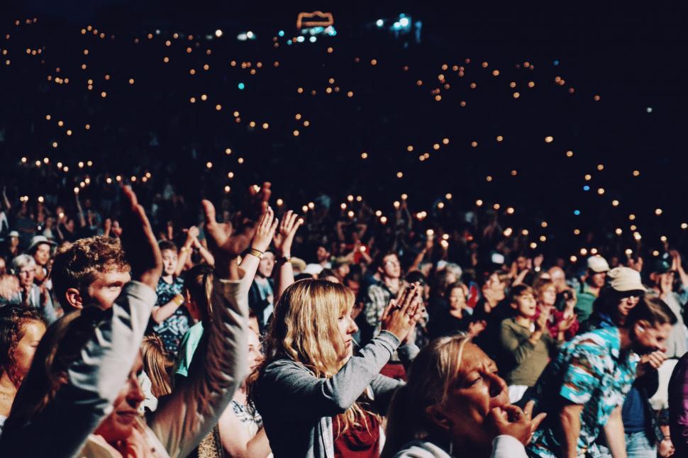 Crowd of fans singing together at a live concert, representing human connection in music